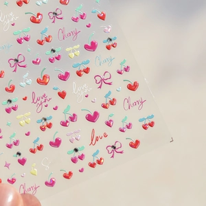 Macro shot of red cherry and heart nail art stickers with sparkling crystal diamond accents