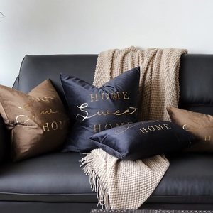 Velvet decorative pillows with gold Home Sweet Home lettering on a leather sofa