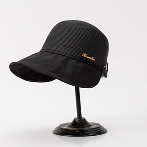 Detail of black straw visor with wave brim and golden Bosenlin metal logo accent