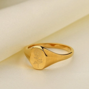 Anello girasole in acciaio inossidabile dorato 18K su sfondo in tessuto beige
