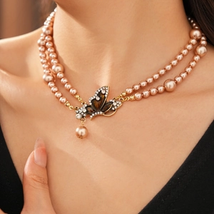 Detail of vintage double-layer pearl necklace with rhinestone butterfly pendant on model