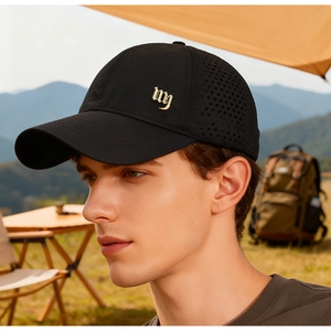 Close-up of black breathable mesh trucker hat with gold metal logo in sunset setting