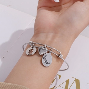 Minimalist silver wire bracelet with heart and birth flower charms worn on wrist