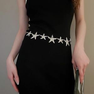 Detailansicht der silbernen Seestern Metall-Kette als Gürtel auf einem schwarzen Kleid
