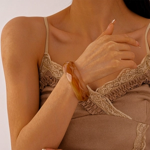 Close-up of wide amber acrylic resin geometric bracelet on a wrist with warm tones