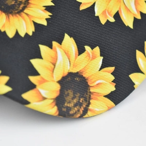 Close-up of bright sunflower print on black high-density twill fabric baseball cap