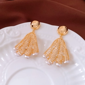 Detail view of 18K gold plated pearl earrings on a vintage white ceramic plate