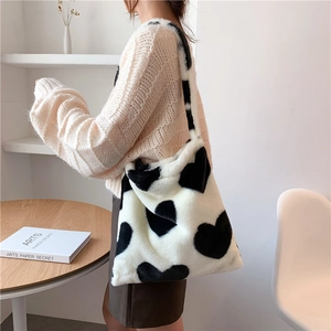 Detail of plush tote bag featuring a black and white heart pattern carried by a model