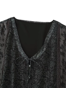 Detail des V-Ausschnitts mit Bändern und Metallknöpfen am dunkel geblümten Chiffonkleid