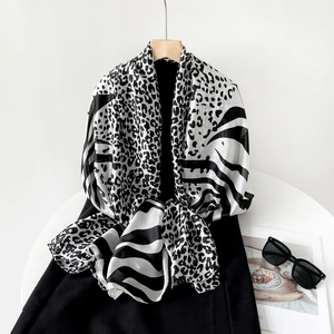 Detailed view of leopard and zebra print silk scarf with fashion sunglasses on white background