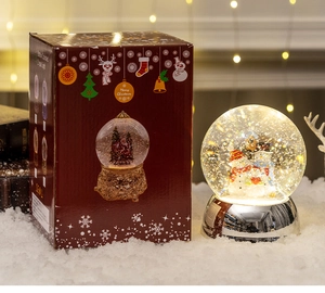 Close-up of a lit Christmas snow globe featuring a snowman family on a silver base