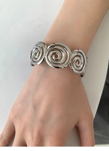 Close-up of a silver spiral open cuff bracelet with triple circular geometric motifs