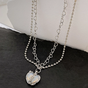 Macro shot of double-layer silver heart necklace with pink zircon stone on stone background
