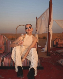Detail of pleated beige resort two-piece set with halter neck in a desert camp setting