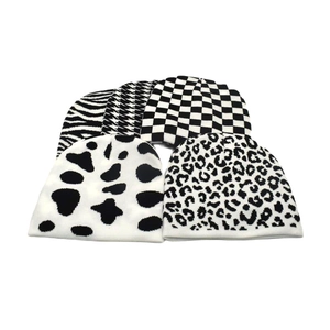 Detailed flat lay of five knit beanies featuring zebra, plaid, and leopard prints