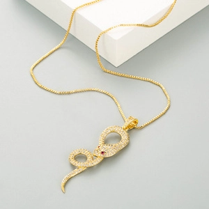 Detailed macro view of a golden snake pendant set with white zircons and red gem eyes