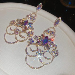 Détail de boucles d'oreilles dorées à pampilles avec strass multicolores brillants