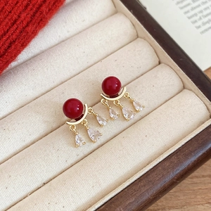 Detailed close-up of red enamel fireworks earrings with transparent pear-shaped pendants