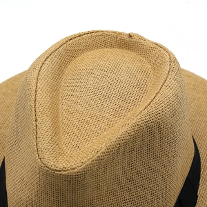 Vue de dessus détaillée de la texture tissée dense et du ruban noir sur le chapeau en paille