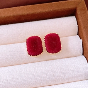 Macro shot of burgundy flocked square stud earrings with golden metallic rope edges