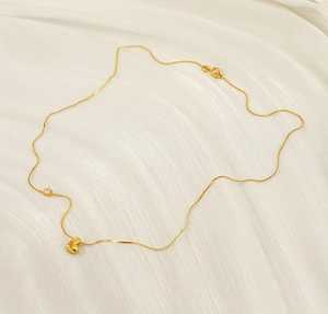 Detail of a gold heart pendant necklace with zircon stone on elegant white silk background
