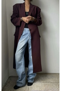 Vue complète d'un trench-coat long sombre avec un jean large et des bijoux