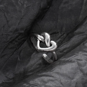 Detailed view of vintage silver heart knot ring with aged metallic texture on silk cloth