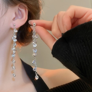 Close-up of long silver tassel earrings with sparkling cubic zirconia on model