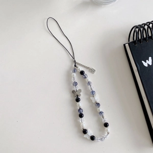 Detail of beaded phone strap featuring a silver Good Luck tag and colorful butterfly charms
