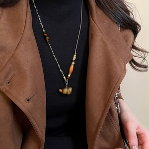 Tiger eye stone gourd pendant necklace on a model wearing a brown suede coat