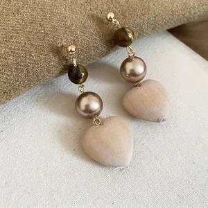 Vintage heart earrings with tiger eye stone and pearls on a textured background