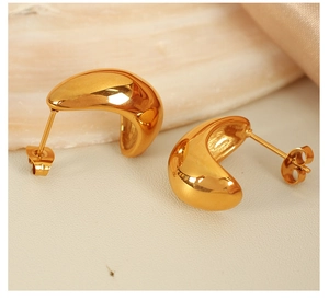 Macro view of gold minimalist chunky C-shape hoop earrings on a soft cream background