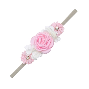 Detailed view of handmade fabric roses and rhinestone daisies on a nylon baby headband