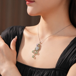 Dettaglio di una collana floreale argento con pietre rosa e verdi su una modella