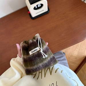 Detail of multi-color striped wool drawstring pouch with brand label on a wooden desk