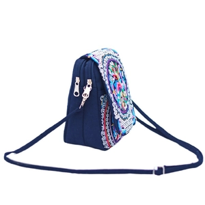 Detail of dual zipper compartments and ethnic floral embroidery on navy crossbody bag