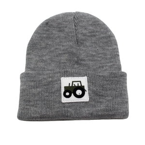 Dark grey knitted beanie for kids featuring a green cartoon tractor patch on the front
