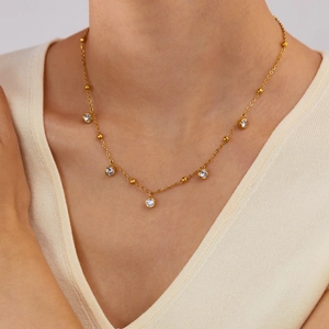 Elegant gold necklace with circular zircon pendants and beads on a model's neck
