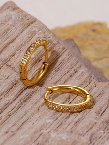 Close-up of 18k gold-plated hoop earrings with clear zircon stones on natural stone base
