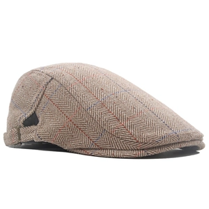 Close-up of British tweed flat cap with herringbone pattern and adjustable metal buckle
