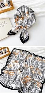 Detail of silk scarf with orange floral print, black borders, and elegant knot styling