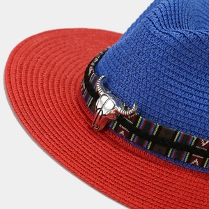 Detail of western straw hat featuring a silver bull skull pendant and ethnic striped ribbon