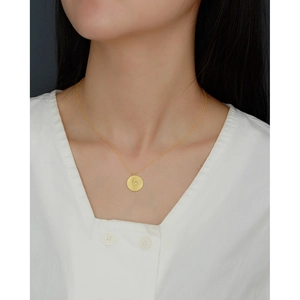 Elegant gold pendant necklace featuring a circular snake embossed charm on a fine chain
