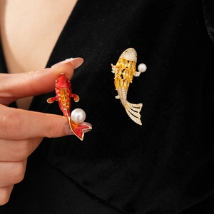 Detailed macro view of carp brooches with red enamel, yellow crystals and white pearls