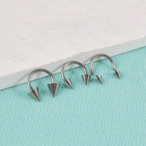 Three G23 titanium horseshoe rings with cone spikes in varying sizes for body piercings