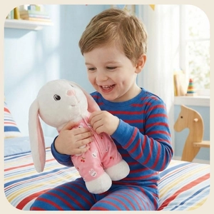 Smiling child hugging a soft white plush rabbit toy wearing pink floral pajamas
