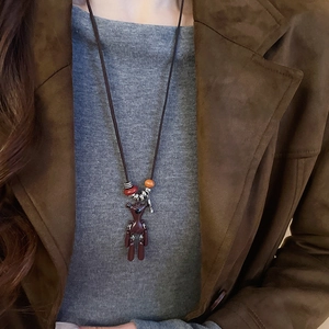 Close-up of retro ethnic long sweater necklace with brown cord and animal pendant
