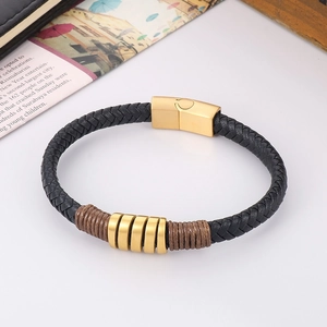 Close-up of a men's black woven leather bracelet with matte gold magnetic clasp and rings