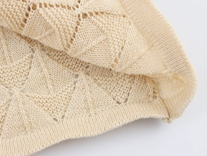 Detailed close-up of beige pointelle knit fabric with ribbed edge craftsmanship