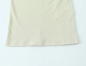 Detailed macro view of beige ribbed cotton top showing high-quality hem stitching